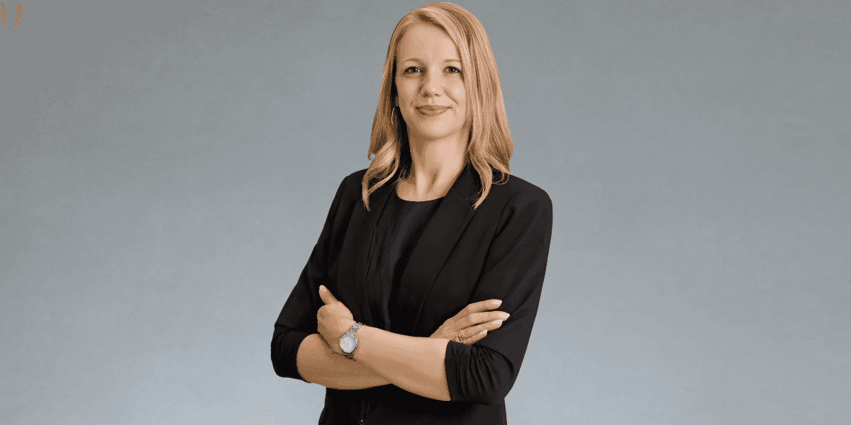 Julia Biro, Founder and CEO of WeDoSkin, stands confidently in a black blazer against a neutral background.