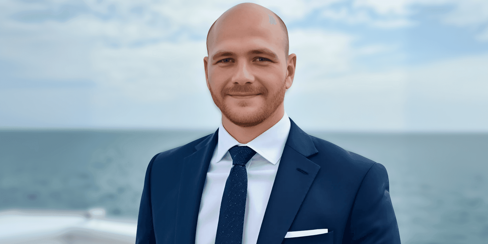 Man in a suit smiling in front of the ocean, representing M3DS Academy's global leadership in 3D education.