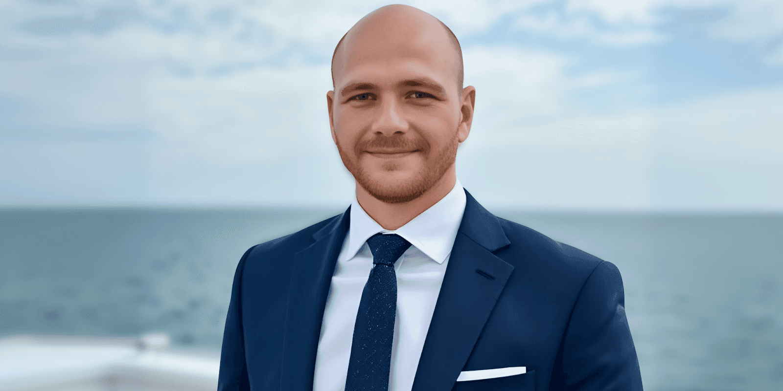 Man in a suit smiling in front of the ocean, representing M3DS Academy's global leadership in 3D education.