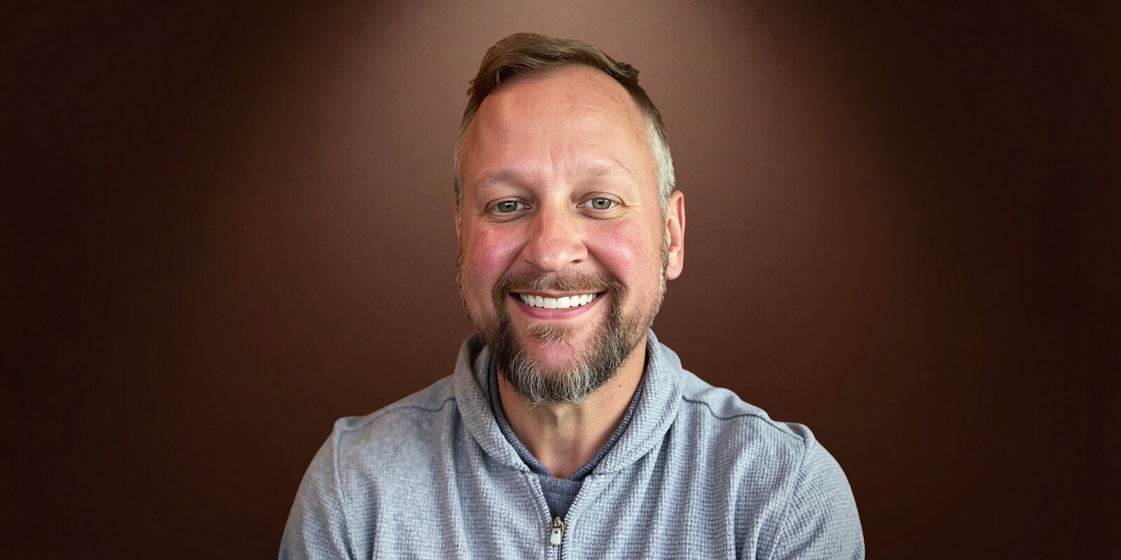 A smiling man with a beard in a blue shirt, representing Marketing Mike, founder of The Fractional CMO Team.