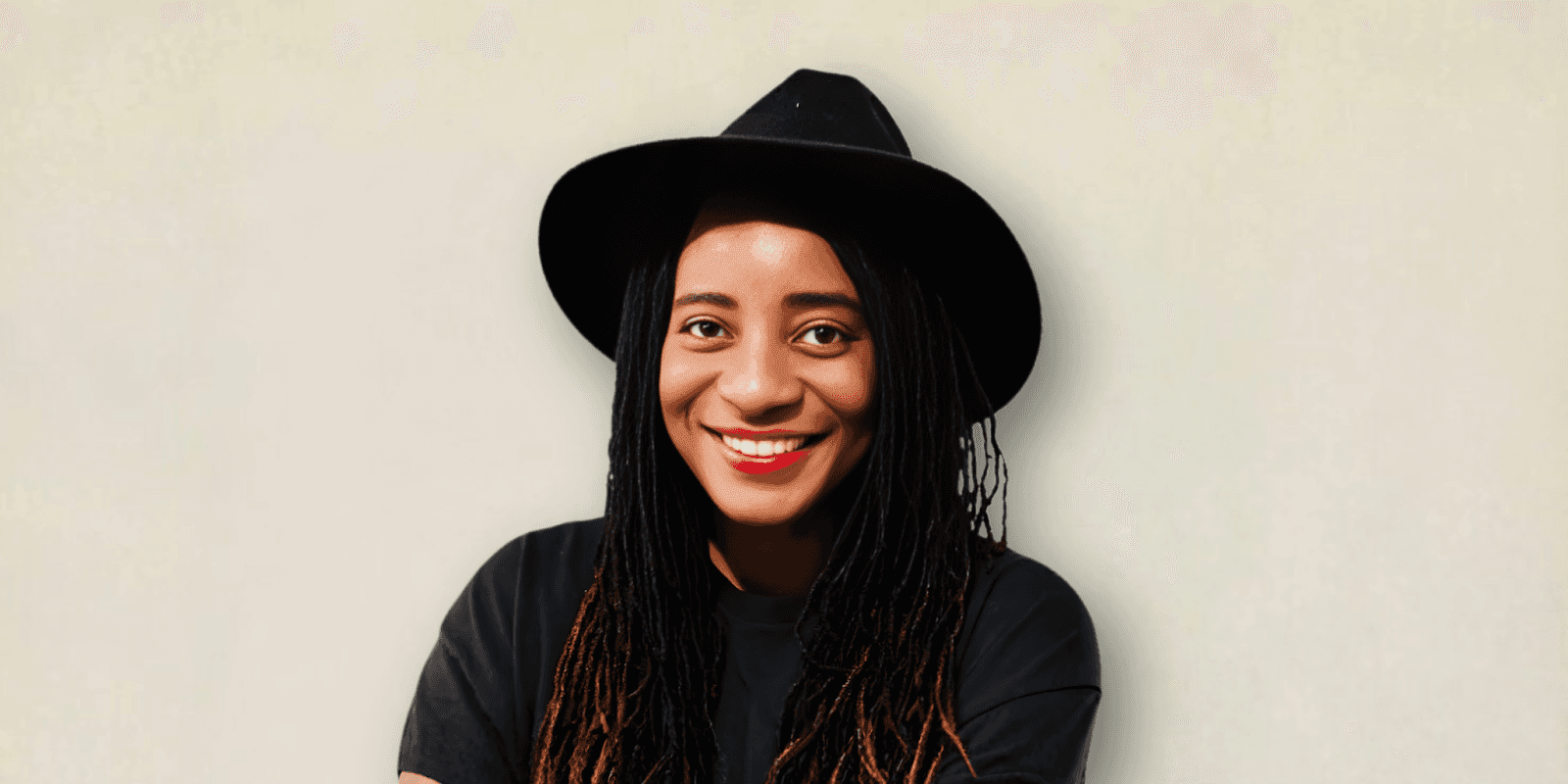 A smiling woman wearing a black hat, promoting self-care and wellness through her work, as outlined by Cheri Darling.