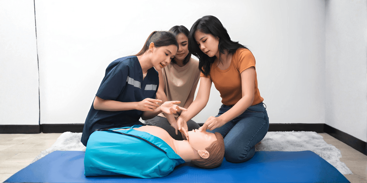 Caregivers practicing Basic Life Support (BLS) on a mannequin, highlighting the importance of emergency preparedness in home care.
