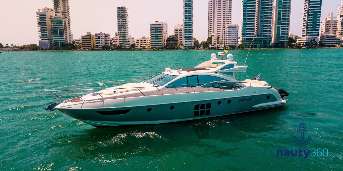 White luxury motor yacht cruising near a city skyline on clear turquoise coastal waters.