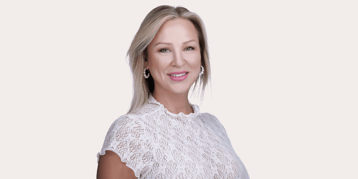 Professional headshot of smiling blonde woman in white lace top for real estate and business branding