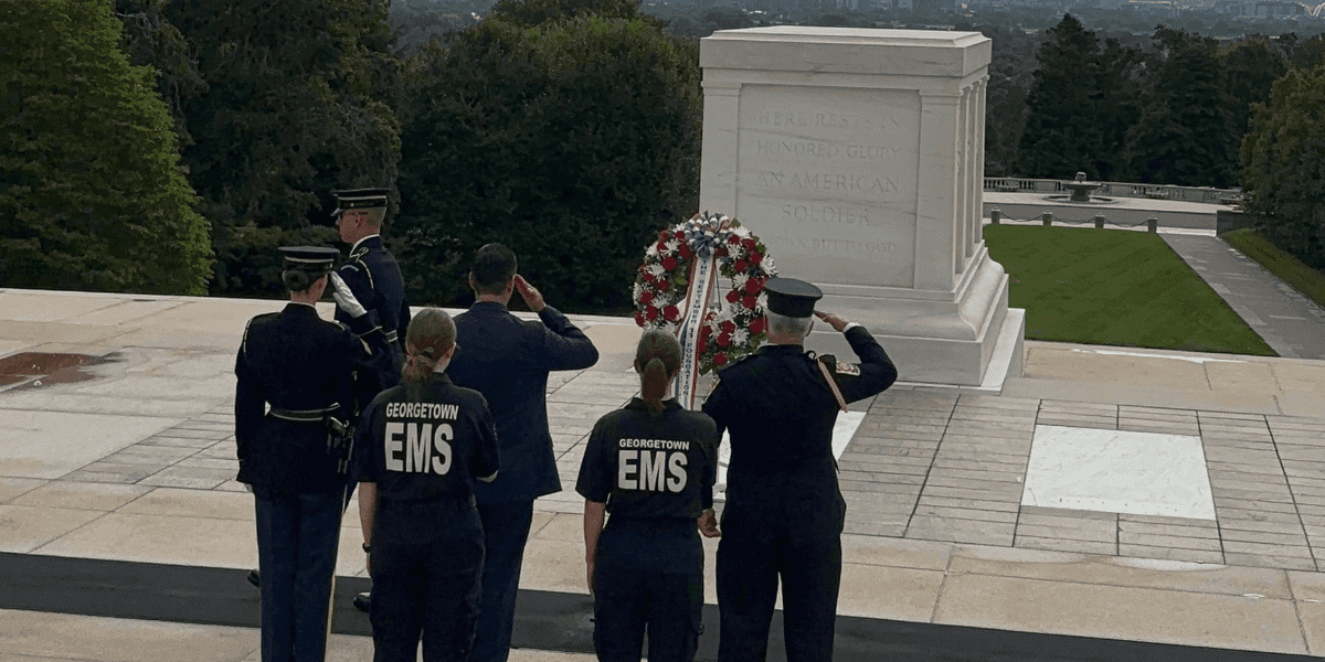Wreath-laying ceremony at Arlington National Cemetery by Georgetown EMS and military personnel, honoring the legacy of 9/11 victims.