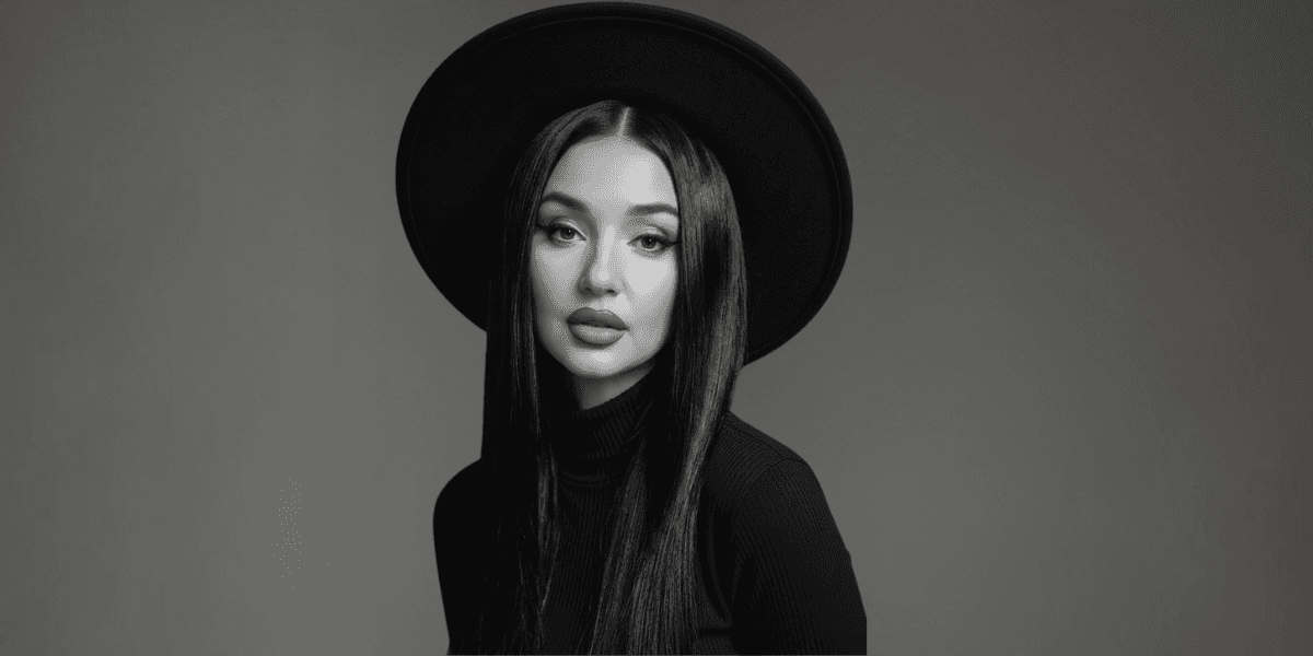 Black-and-white portrait of a woman in a wide-brim hat, gazing calmly at the camera.