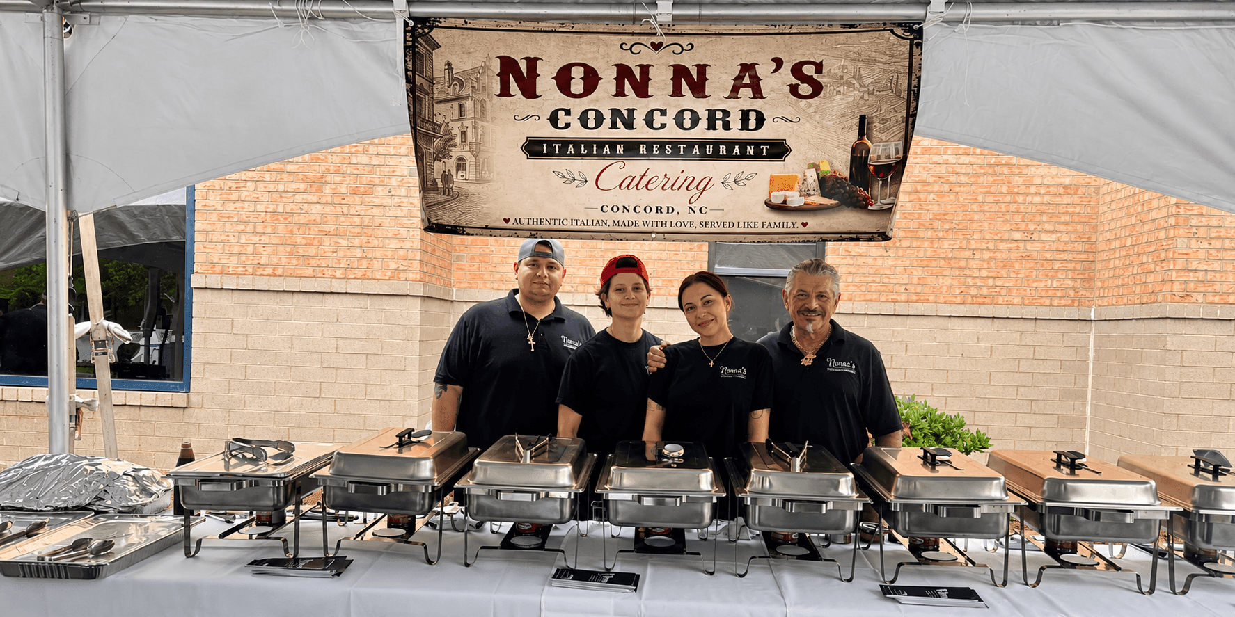 Nonna's Italian Restaurant catering team stands behind buffet stations beneath a catering banner.