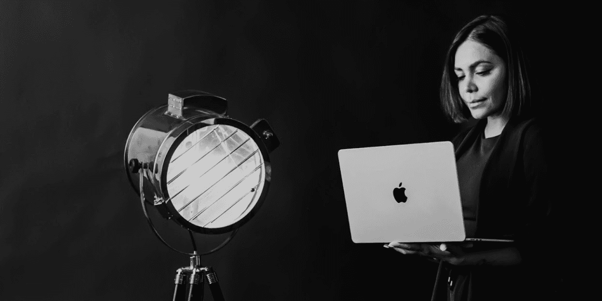 Dr. Reggie Kaur, author of Unlearning Success, stands thoughtfully with a laptop, reflecting her journey to redefine fulfillment.