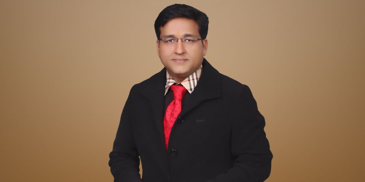 Portrait of Himanshu Pant, managing director of Epique Real Ventures, wearing a black coat and red tie.