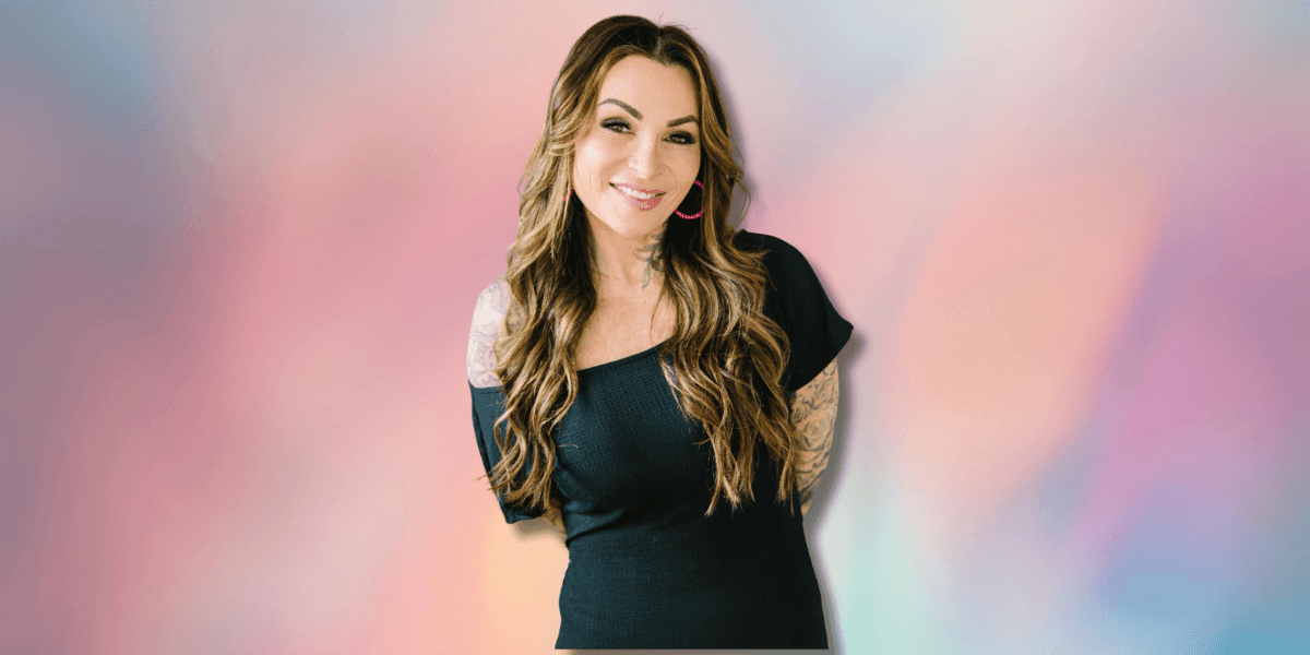 "Smiling woman with tattoos standing against a color