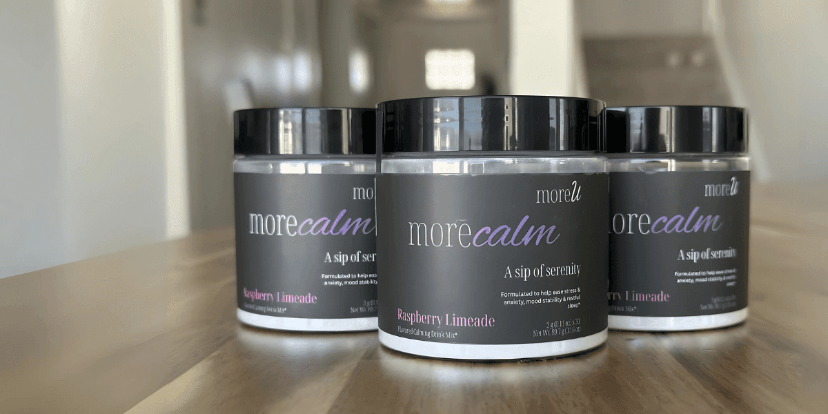 Three jars of moreU morecalm Raspberry Limeade calming drink mix on a wooden table.