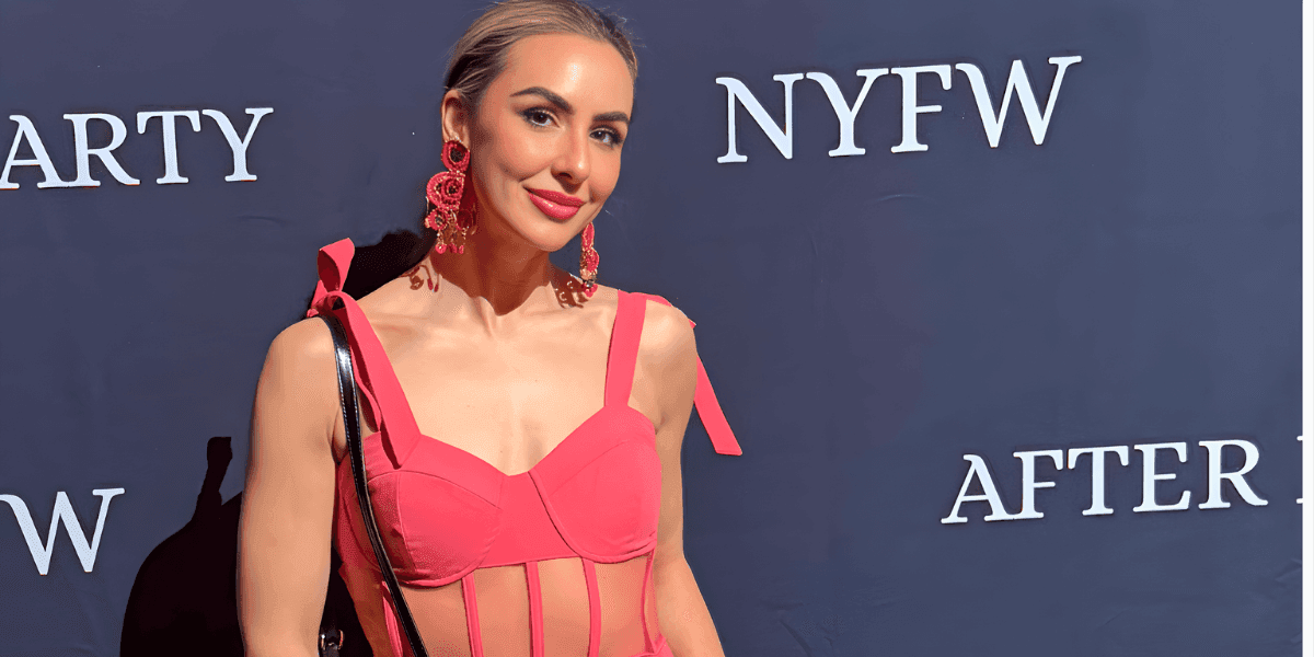 a woman at NYFW wearing a chic pink outfit, with bold earrings, embodying a refined beauty look.