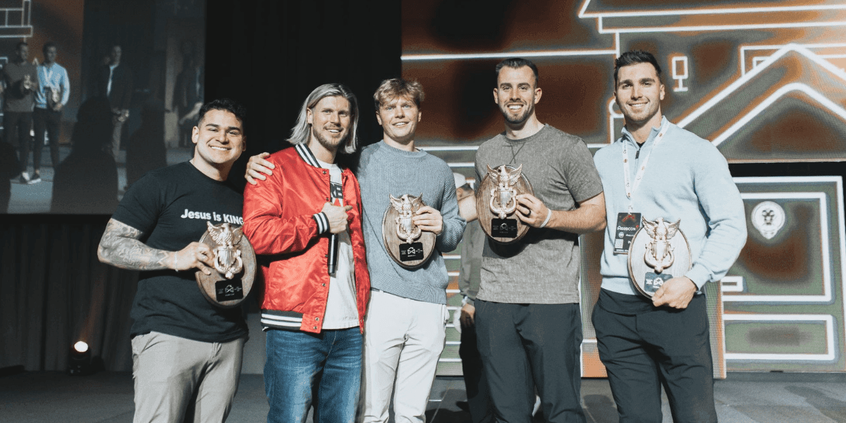Five door-to-door sales representatives pose on stage holding award plaques at a D2D Games event.