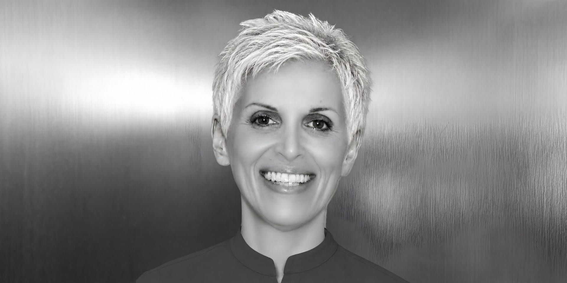 Black-and-white portrait of artist and author Joy Hutchins smiling against a softly lit background.