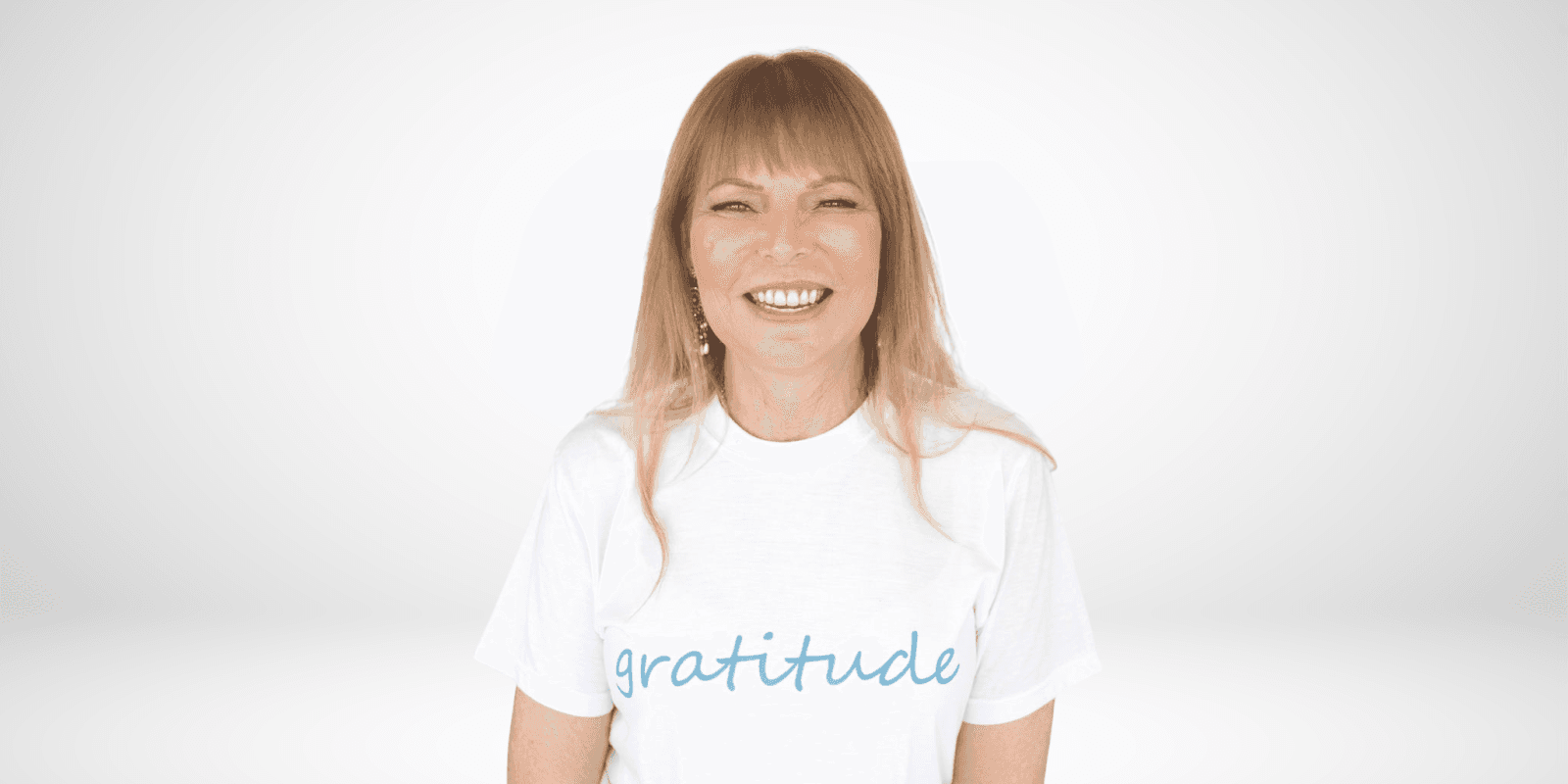 Karel Glazer smiles confidently in a white 'gratitude' t-shirt, embodying her message of financial empowerment and self-worth.