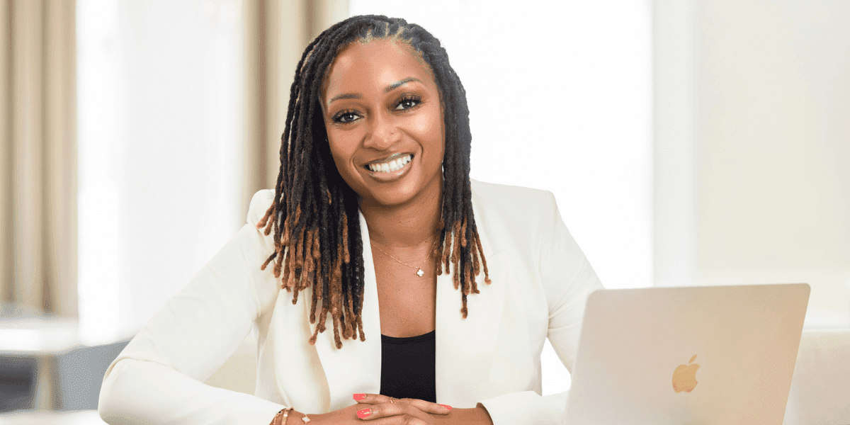 Dr. Jessica Saulsberry seated at a desk beside a laptop, wearing a white blazer.