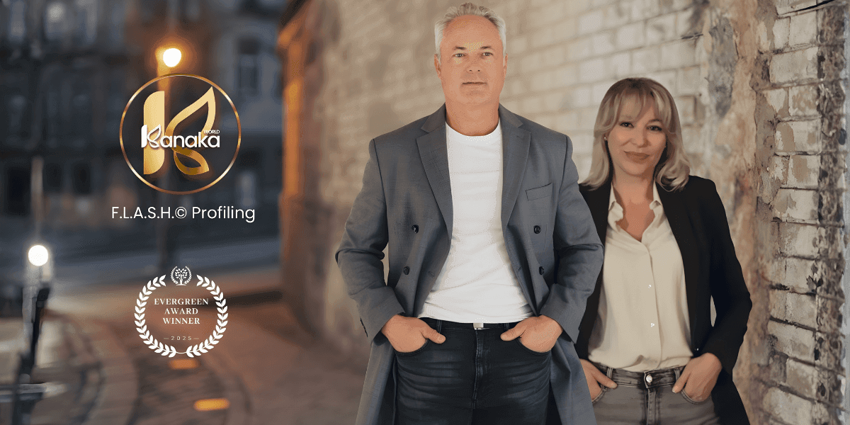 Man and woman leaning against a brick wall in a dimly lit street, both smiling. Logos for "Kanaka F.L.A.S.H.© Profiling" and "Evergreen Award Winner" are visible.