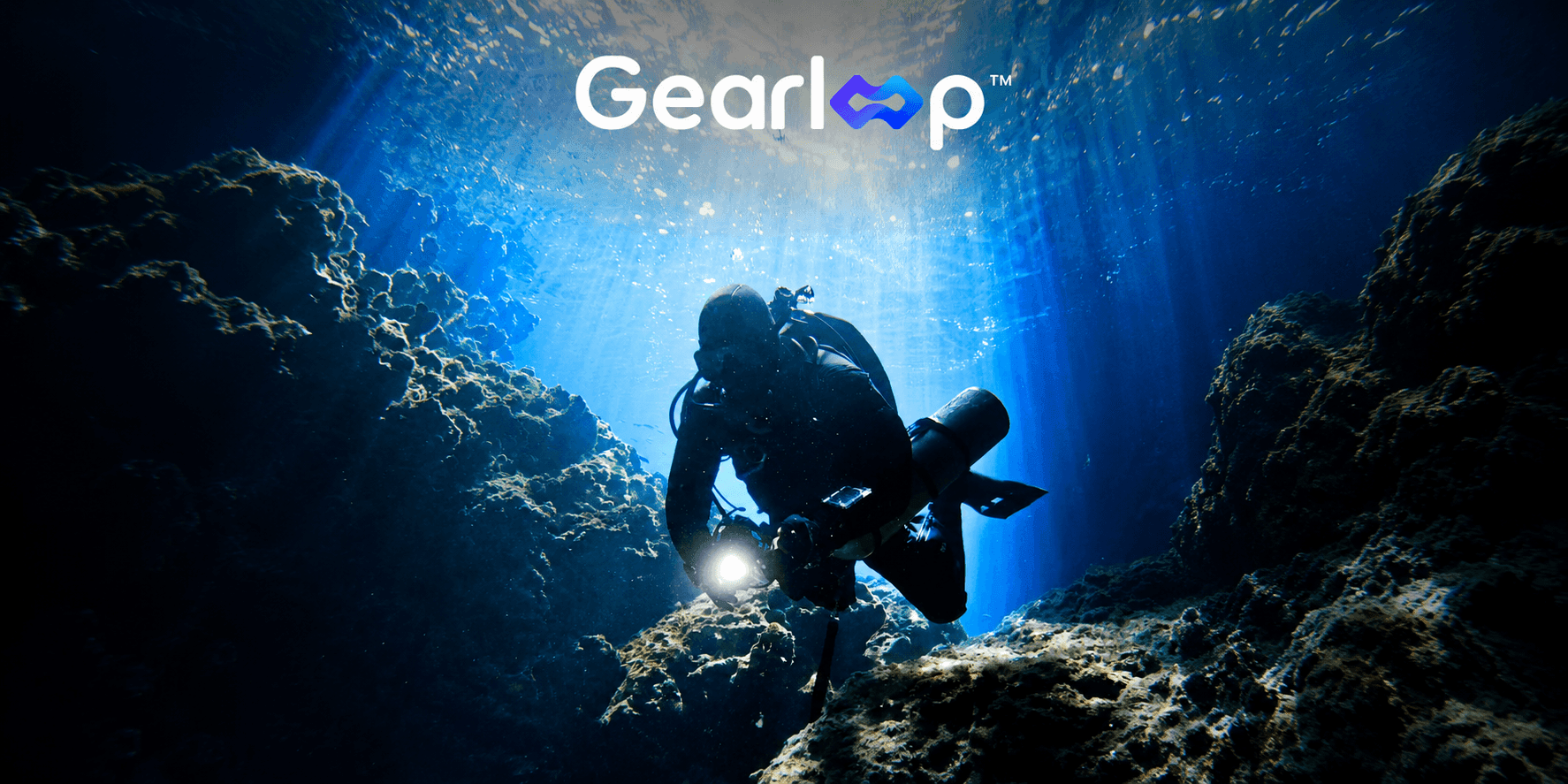Scuba diver exploring an underwater cave illuminated by sunlight beams, with Gear Loop branding above.