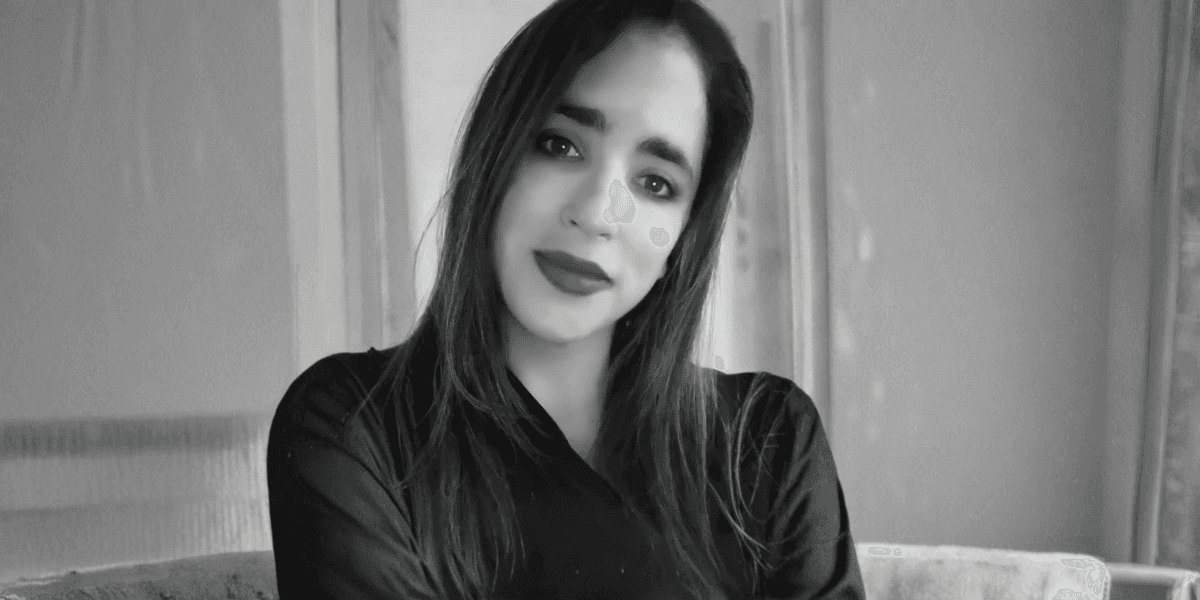 Portrait of a woman with long dark hair, smiling gently, exuding warmth and empathy in a soft, natural setting.