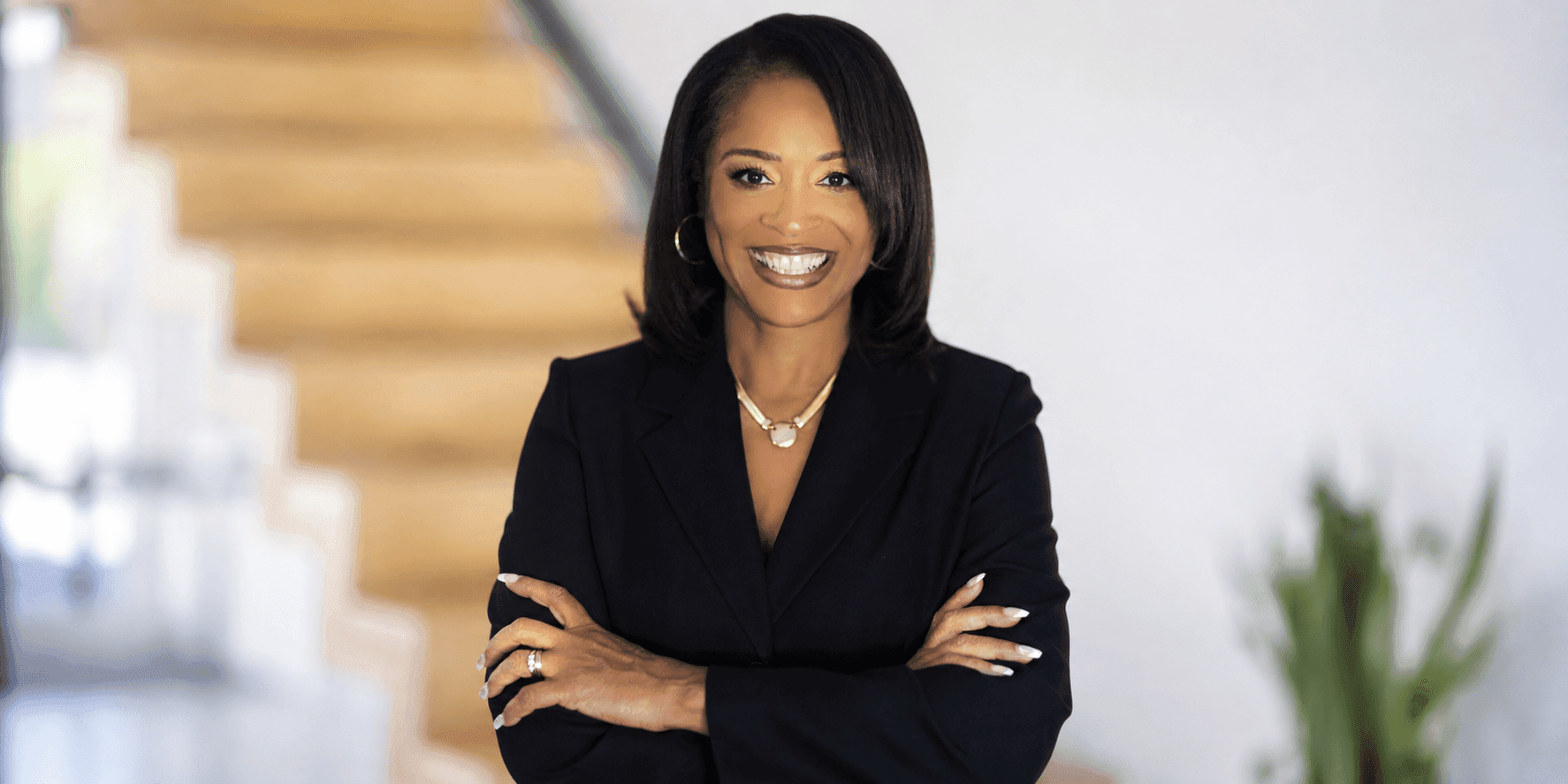 Celeste Warren smiling with folded arms in a black blazer in an office setting.