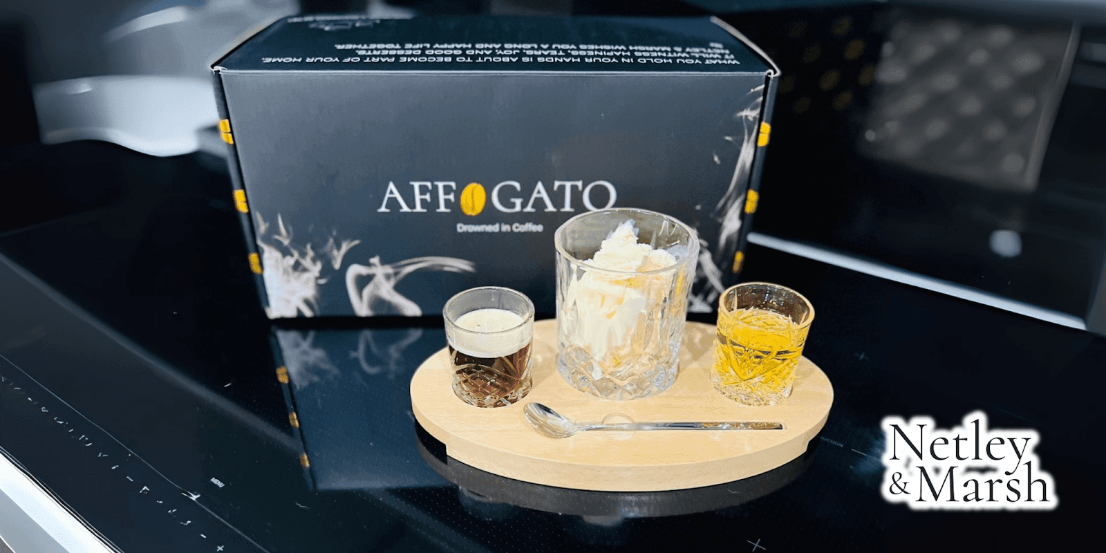 A beautifully presented Affogato dessert with a shot of coffee, a glass of whiskey, and a scoop of vanilla ice cream served on a wooden tray, with the Affogato box in the background.