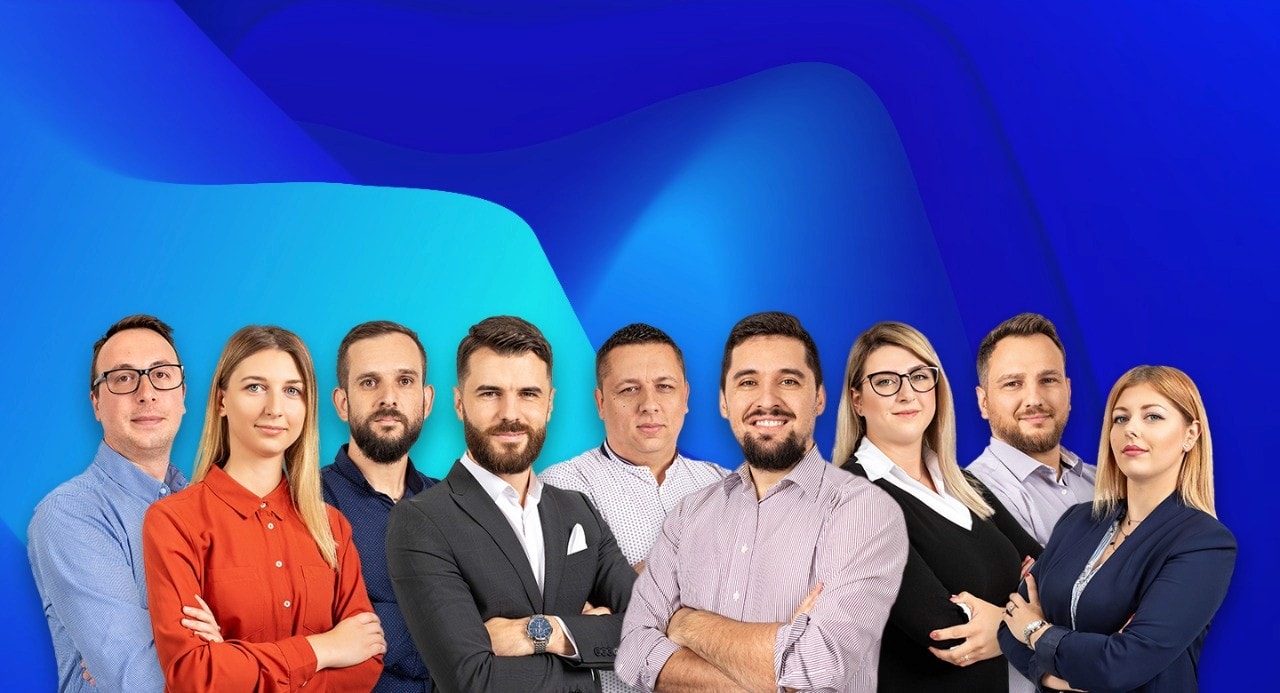A professional team of nine individuals, posing in front of a vibrant blue and green background. The diverse group includes both men and women dressed in formal and business casual attire, representing a corporate environment. The image highlights a unified, skilled team with confident body language.
