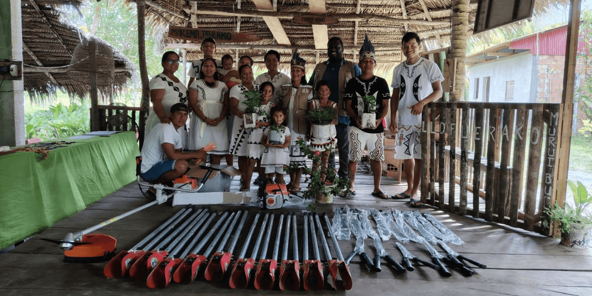 Community members display donated forestry tools and plants inside an Amazon village gathering space.