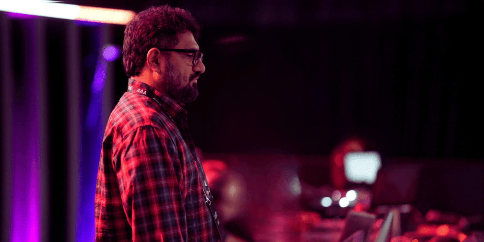 Becket Tundatil, founder of Fireflies Creative Technologies, observes a live lighting setup under pink stage lights, showcasing immersive Vision Pro innovation.
