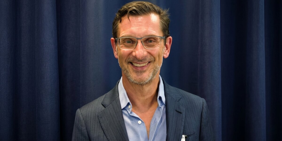 Dr. Mark Kohout smiling in a suit during a professional portrait.