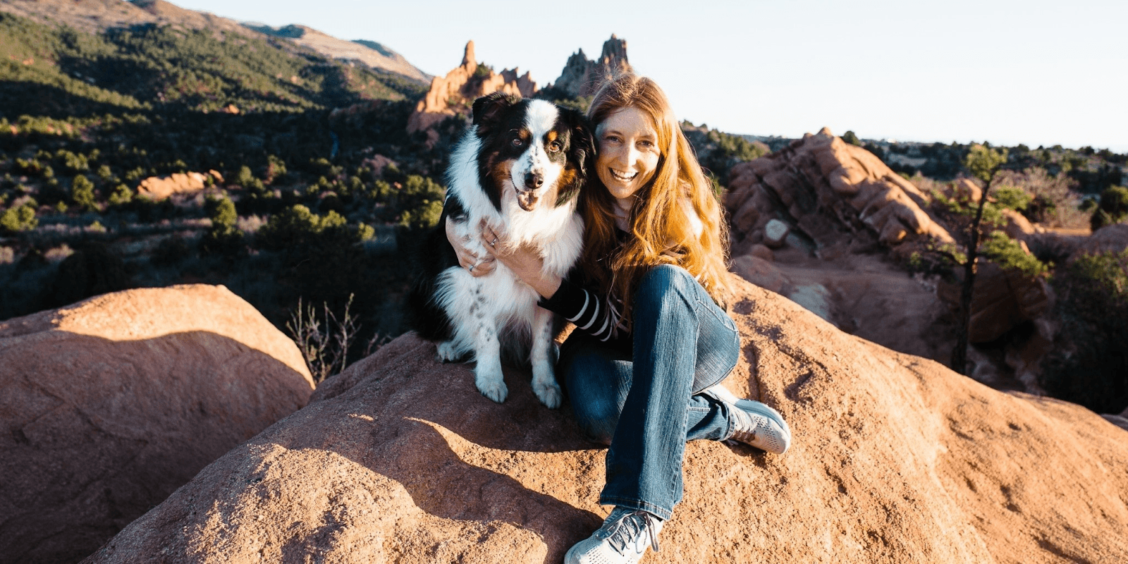 Andrea Bogle with her Australian Shepherd, showcasing the bond built through science-based training methods in a scenic outdoor environment.