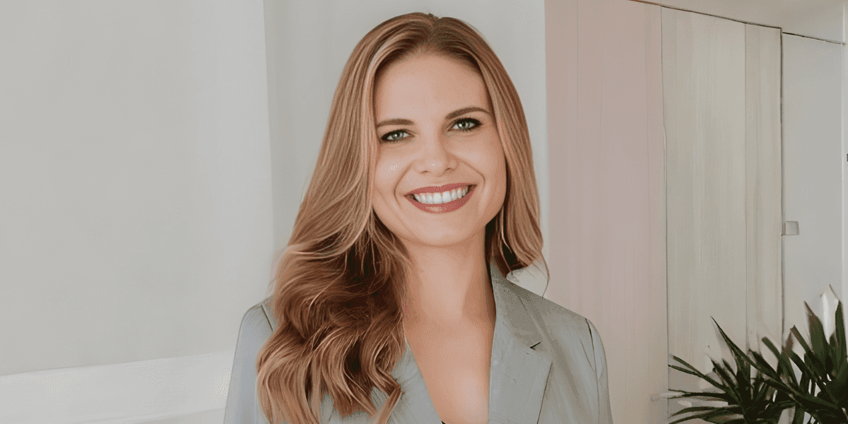 Angela Porrelli smiling in a light gray blazer inside a modern office.
