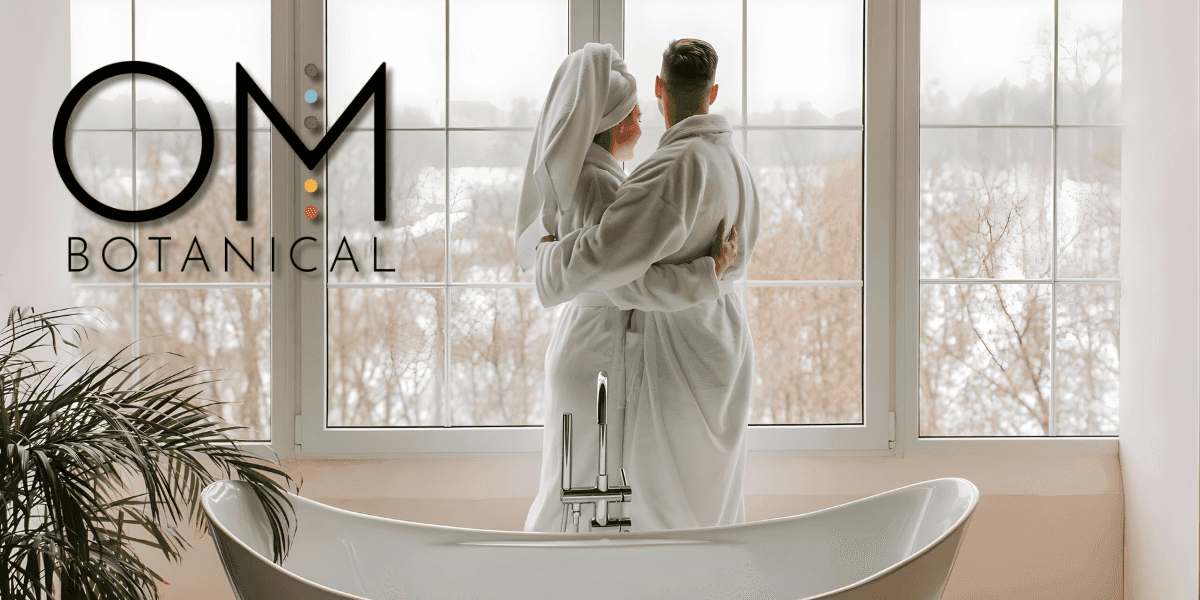 A couple in bathrobes enjoys a serene moment together by the window, reflecting OM Botanical’s holistic skincare approach.