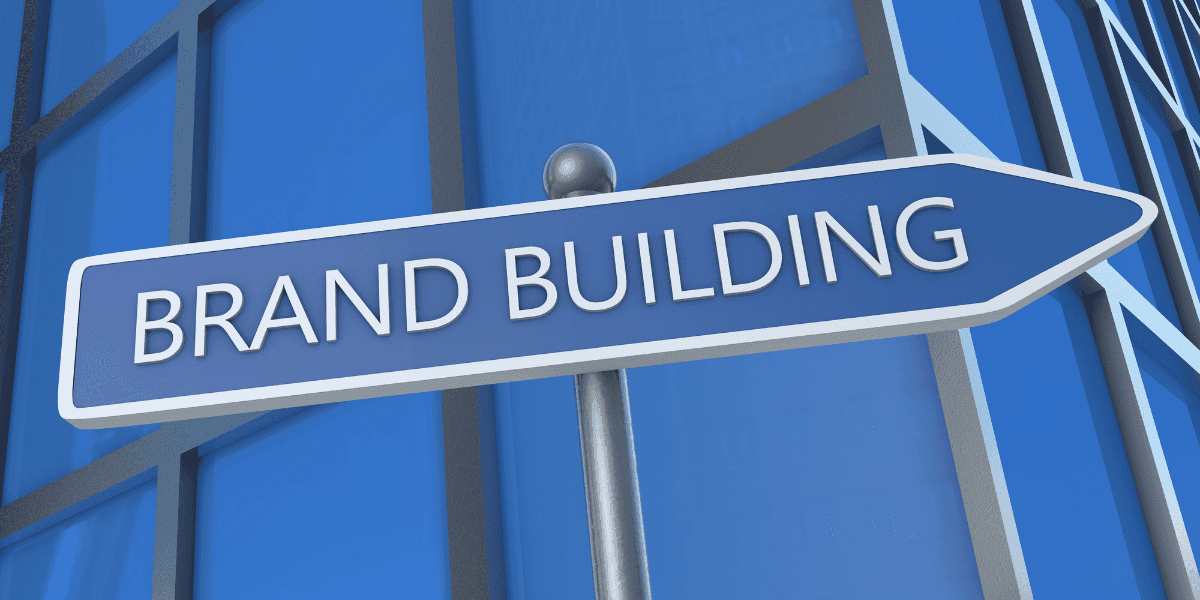 Brand Building sign pointing forward against a contemporary blue corporate building backdrop.