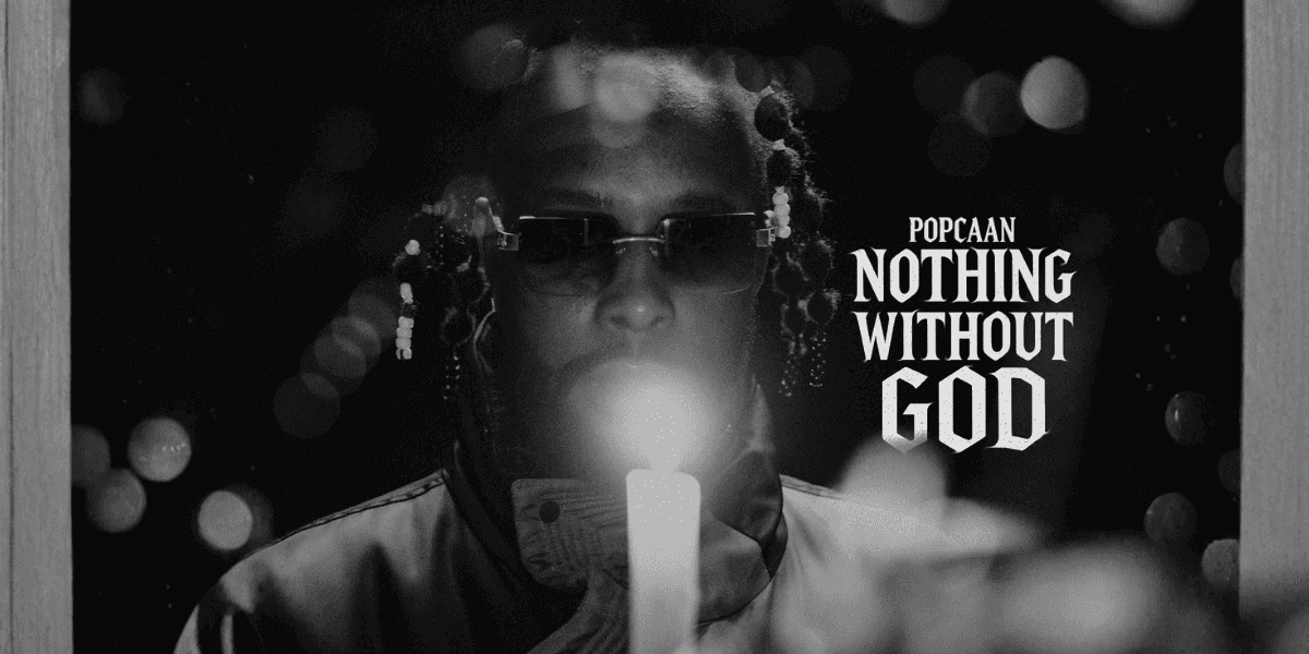 Popcaan holding a candle, reflecting spirituality, with the album title 'Nothing Without God' prominently displayed.