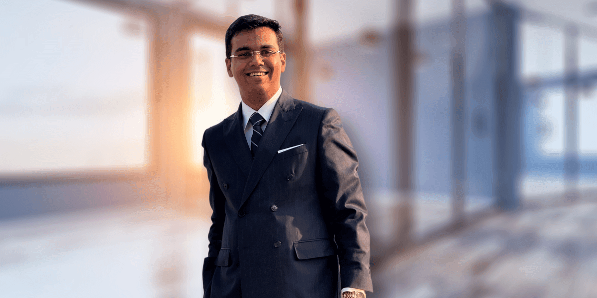 Professional man in a business suit, smiling confidently in a modern office setting with natural light.