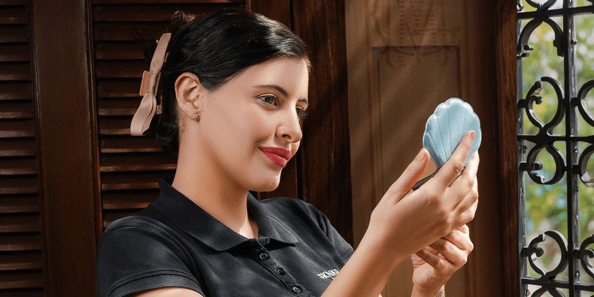 Michelle Espinosa Badias holding a handheld mirror during a personalized skincare consultation at SKNKR BAE!