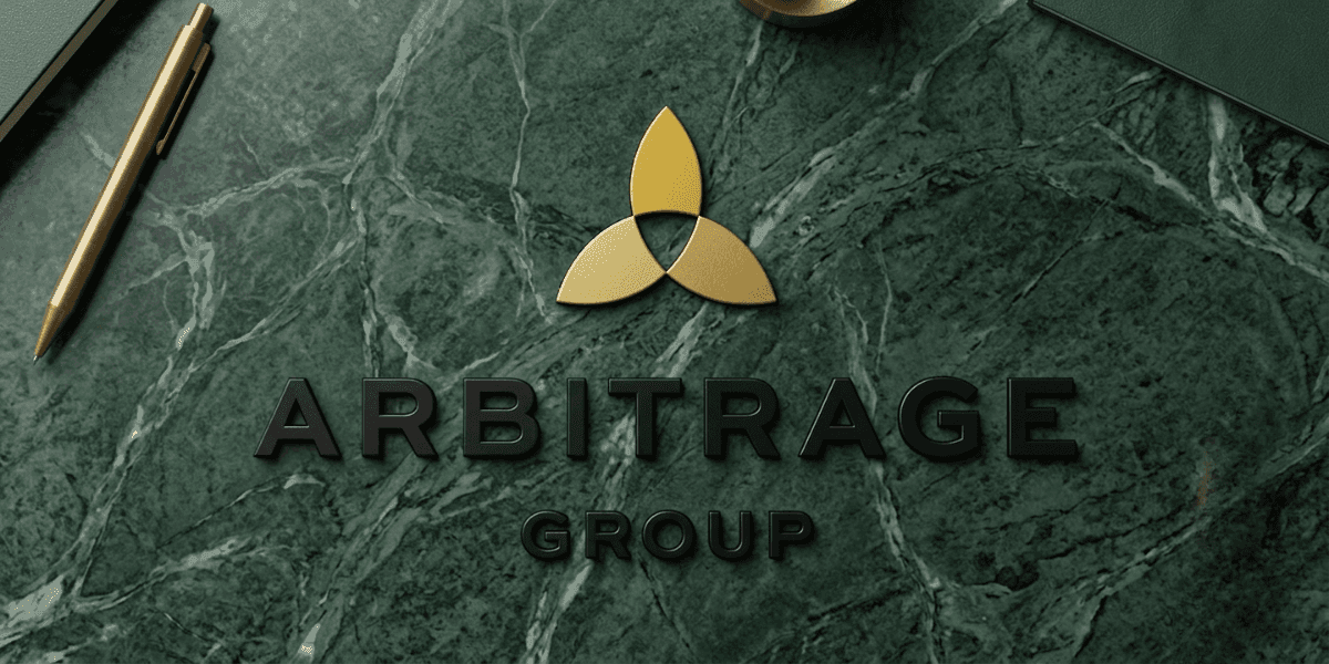 Arbitrage Group logo on green marble desk with gold pen, symbolizing luxury London real estate strategy.