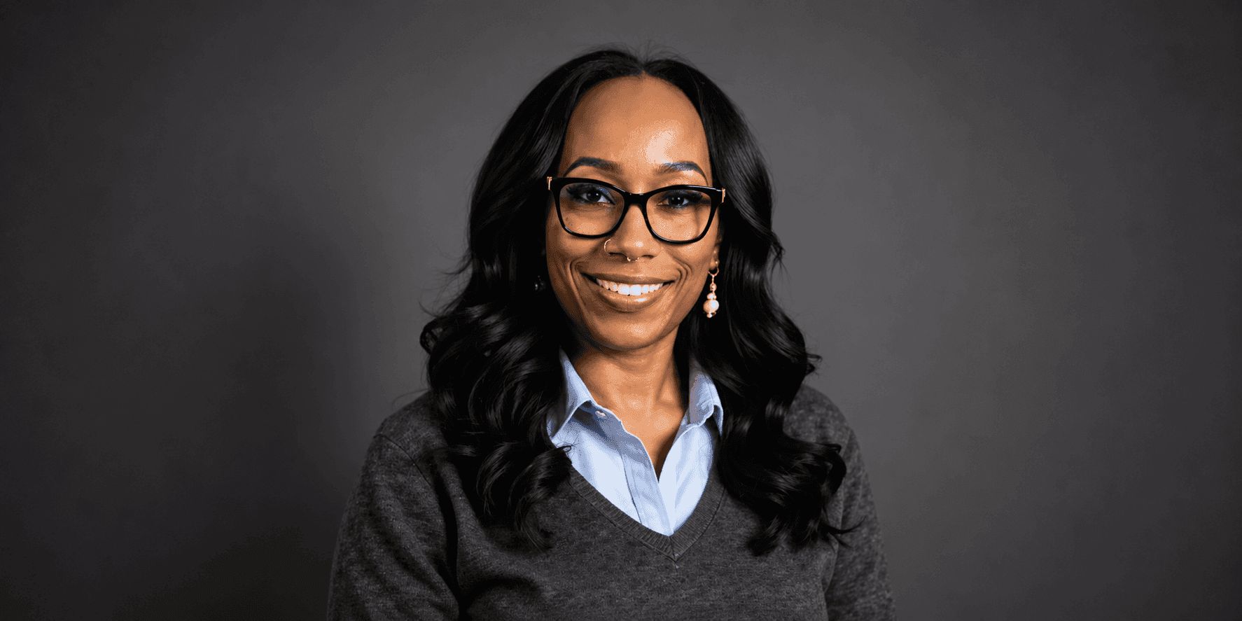 Professional headshot of Dr. Stacey L. Horn smiling while wearing glasses and business attire against a dark background.