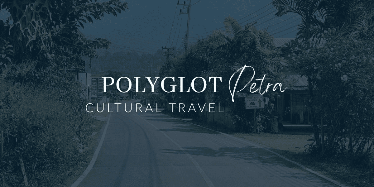 "A scenic road view surrounded by lush greenery with the Polygot Petra Cultural Travel logo in the foreground, emphasizing cultural travel and adventure tourism."