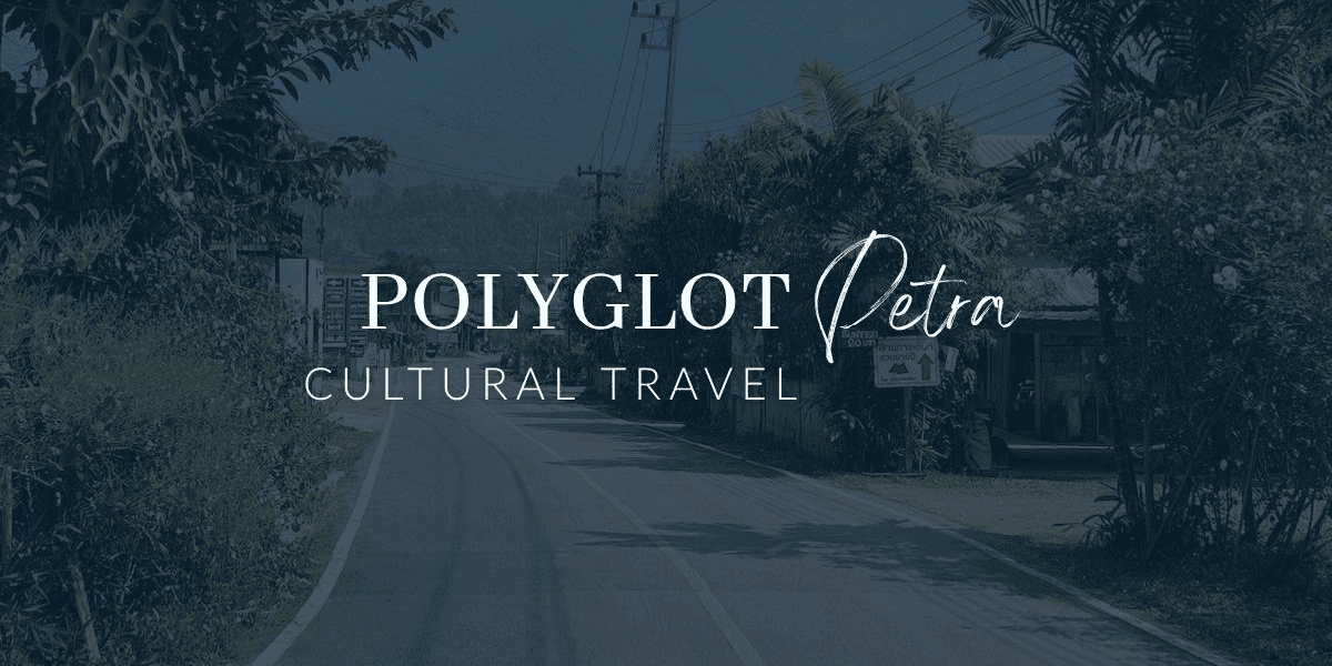 "A scenic road view surrounded by lush greenery with the Polygot Petra Cultural Travel logo in the foreground, emphasizing cultural travel and adventure tourism."