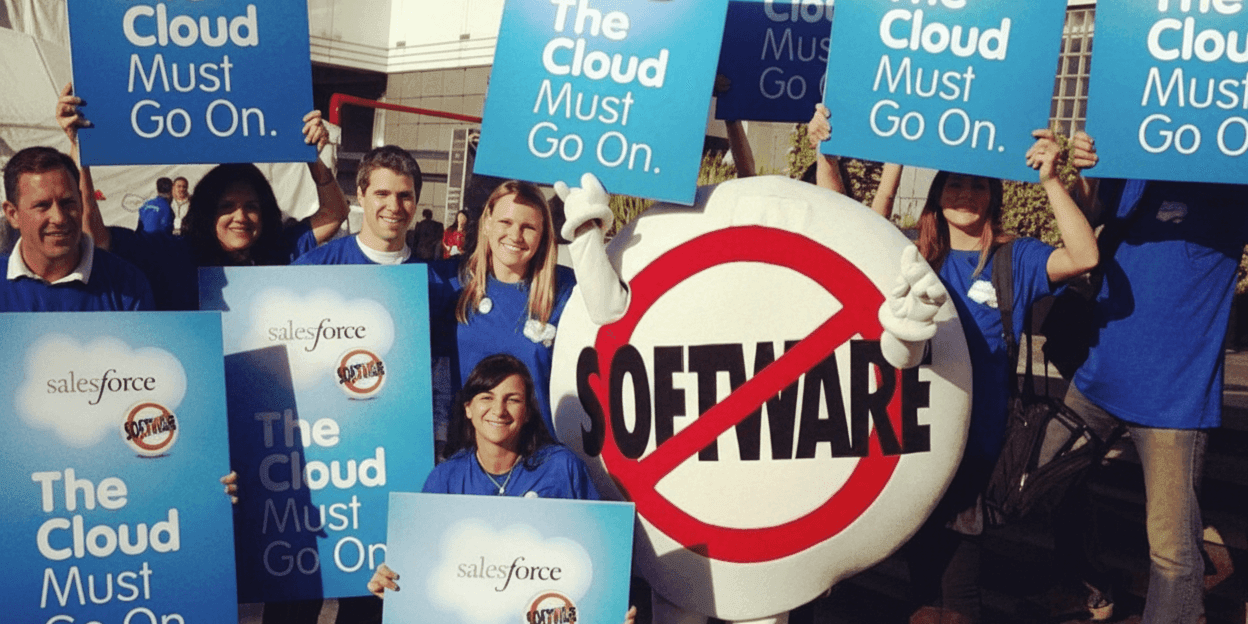 Protesters holding signs at a Salesforce event, referencing the company's original 'No Software' protest, mimicking its 2000 stunt.