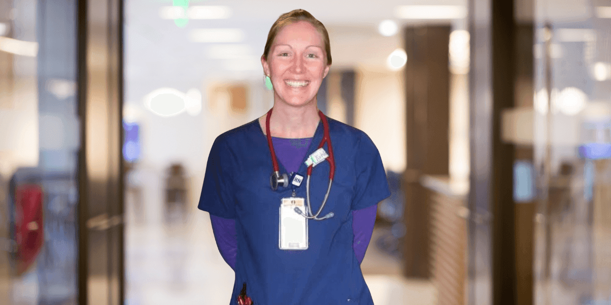 Smiling nurse Elizabeth Ann Ison stands in hospital hallway, wearing scrubs and stethoscope, symbolizing compassionate caregiving.