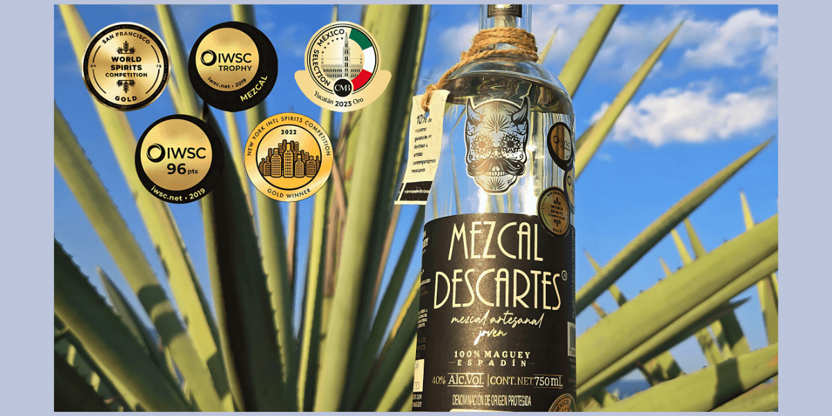 A bottle of Mezcal Descartes displayed with awards, showcasing craftsmanship, sustainability, and Mexican artistry.