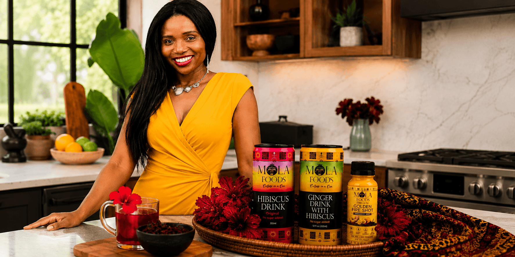 LaFortune Djabea standing with Mola Foods hibiscus beverages and wellness products in a modern kitchen.