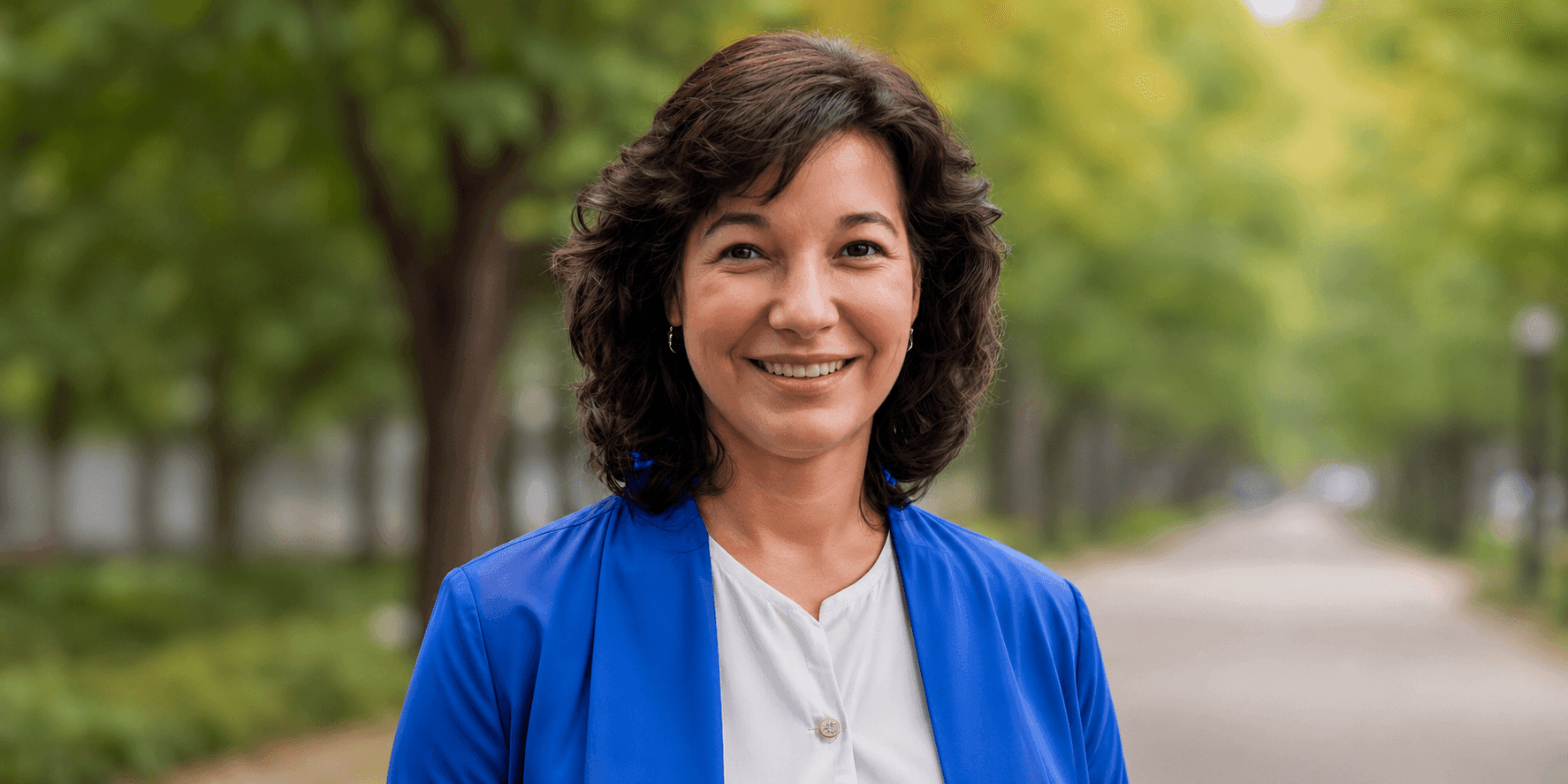Dr. Leott smiling outdoors in a blue blazer, representing her role as a women’s health educator.